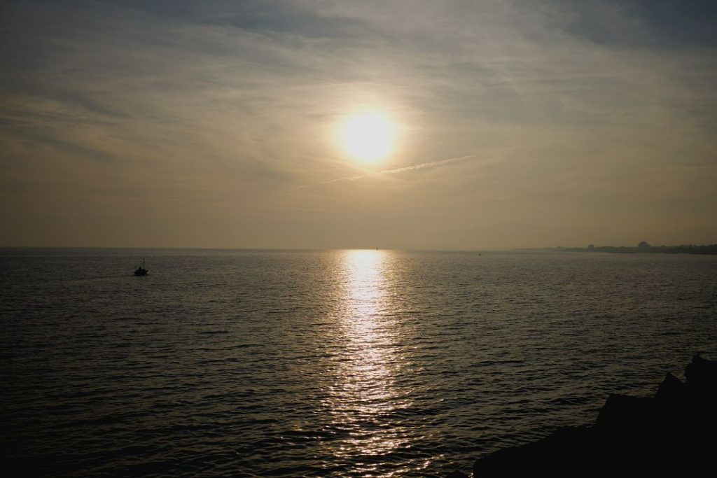 Puesta de sol reflejado en el mar y barco